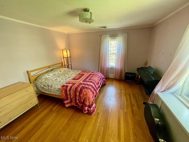bedroom featuring visible vents, ornamental molding, and hardwood / wood-style floors