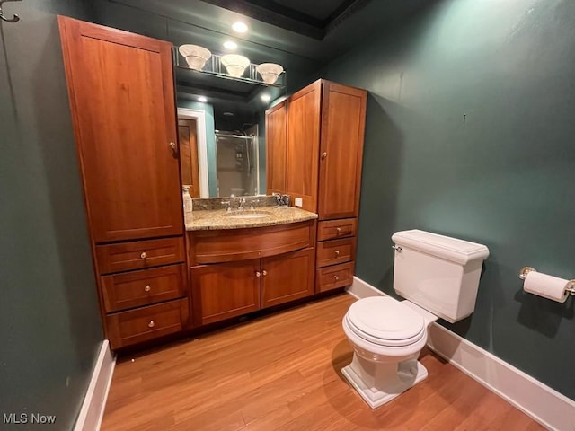 full bathroom with baseboards, a shower with door, toilet, and wood finished floors