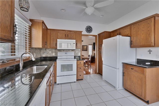 kitchen with a sink, dark stone counters, ceiling fan, and white appliances
