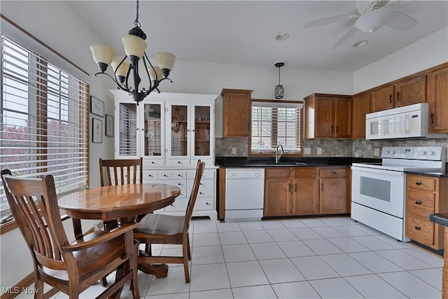 kitchen featuring dark countertops, white appliances, ceiling fan with notable chandelier, backsplash, and pendant lighting