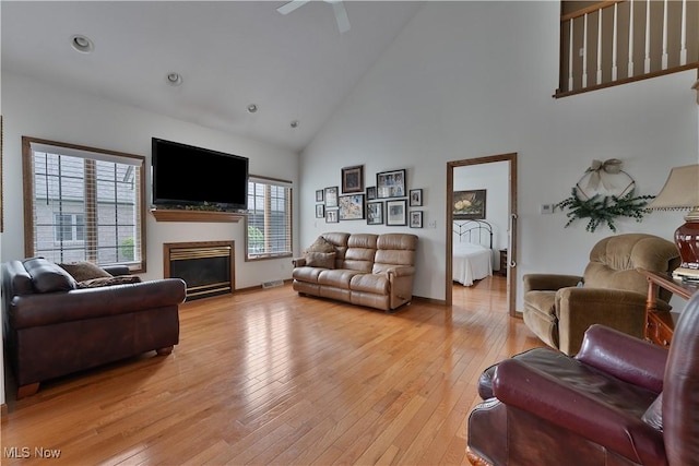 living area featuring ceiling fan, a fireplace, light wood-type flooring, high vaulted ceiling, and recessed lighting