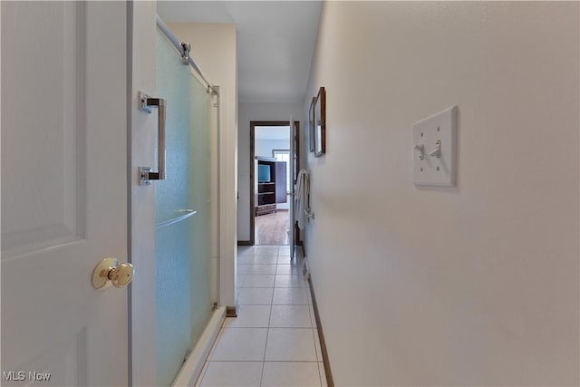 corridor featuring baseboards and light tile patterned floors
