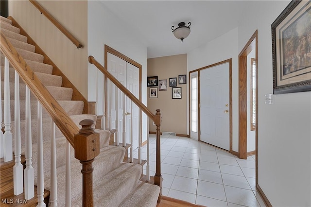 entryway with light tile patterned floors, baseboards, stairs, and visible vents