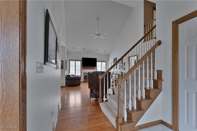 stairs featuring baseboards, ceiling fan, lofted ceiling, and wood finished floors