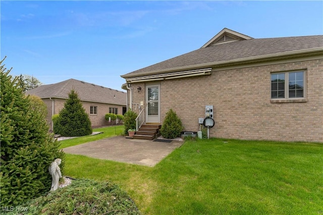 rear view of house featuring a lawn, entry steps, a patio area, and brick siding