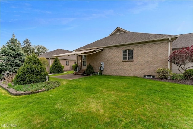 back of property with roof with shingles, a lawn, a patio area, brick siding, and entry steps