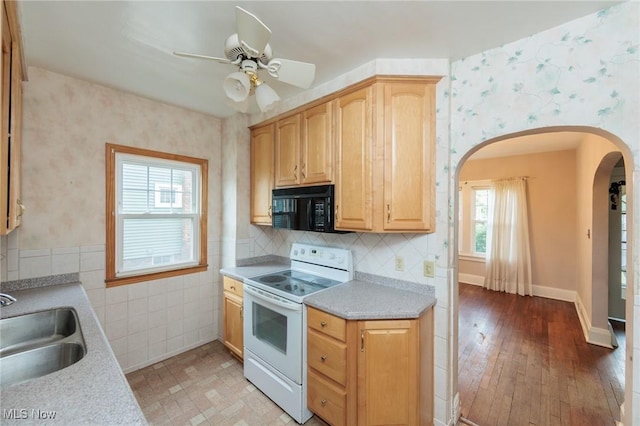 kitchen with electric range, black microwave, a sink, arched walkways, and wallpapered walls