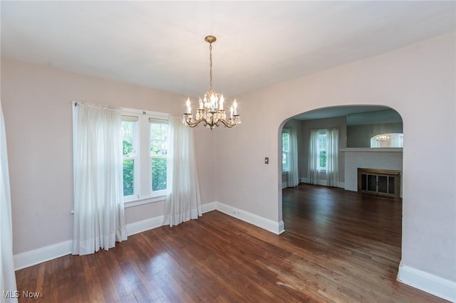 unfurnished dining area featuring an inviting chandelier, baseboards, wood finished floors, and a wealth of natural light