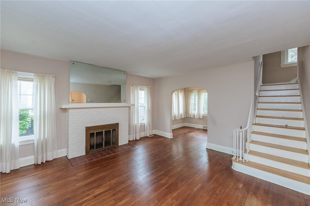 unfurnished living room with baseboards, plenty of natural light, a fireplace, and wood finished floors