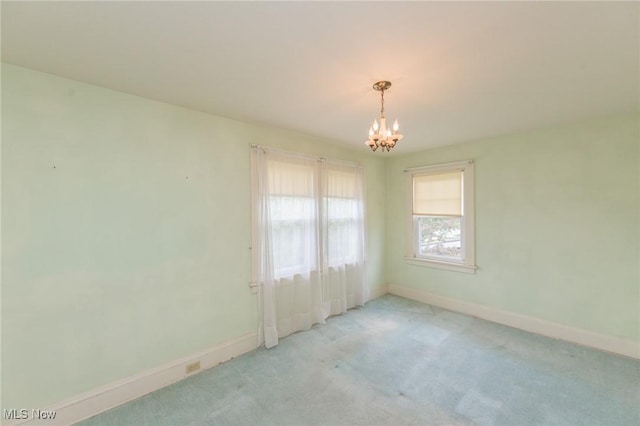 carpeted spare room featuring baseboards and a notable chandelier