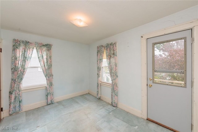 carpeted spare room featuring a healthy amount of sunlight and baseboards
