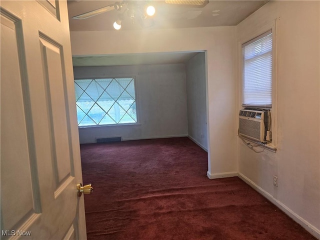 unfurnished room with visible vents, dark carpet, baseboards, ceiling fan, and cooling unit
