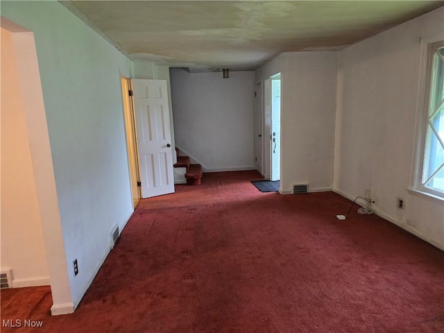 empty room with carpet flooring, baseboards, visible vents, and stairs