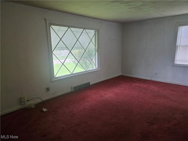 carpeted empty room featuring visible vents and baseboards