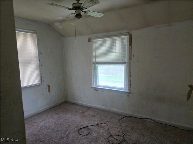 carpeted empty room featuring baseboards, a ceiling fan, and lofted ceiling
