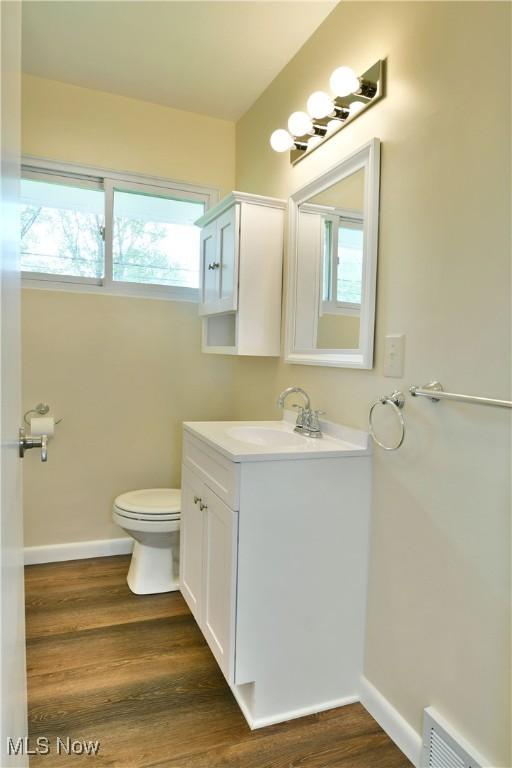5071 Copeland Ave NW, Warren, OH 44483 - bathroom featuring vanity, toilet, baseboards, wood finished floors, and visible vents