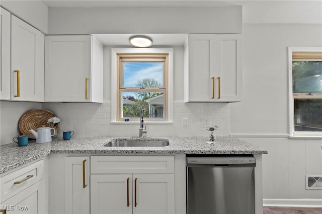 kitchen featuring stainless steel dishwasher, white cabinets, visible vents, and a sink
