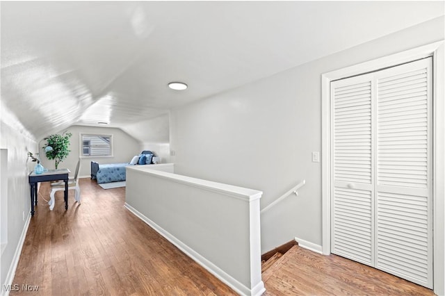 bedroom with baseboards, vaulted ceiling, wood finished floors, and a closet