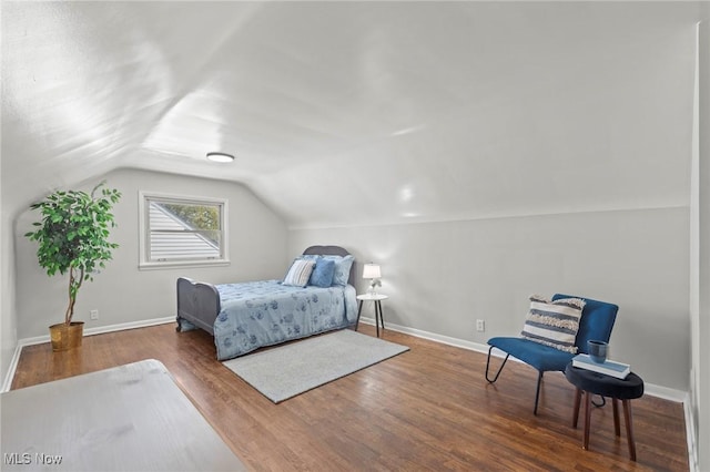 bedroom with baseboards, wood finished floors, and vaulted ceiling