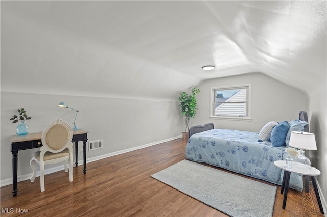 bedroom with baseboards, visible vents, wood finished floors, and vaulted ceiling