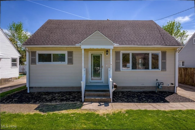 bungalow featuring fence and roof with shingles
