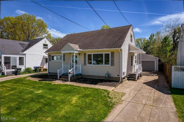 view of front of house featuring roof with shingles, a detached garage, fence, an outdoor structure, and a front lawn