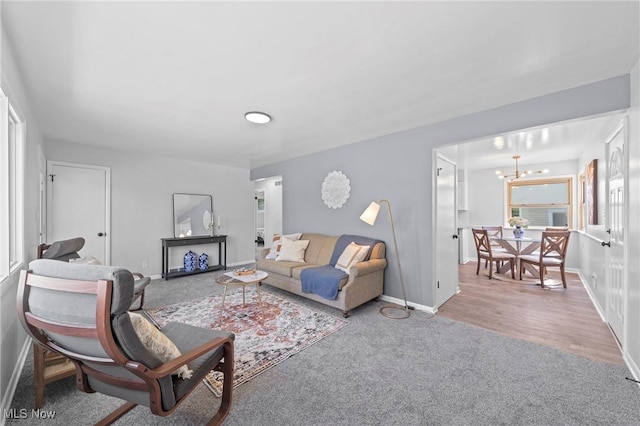 carpeted living room with baseboards and an inviting chandelier