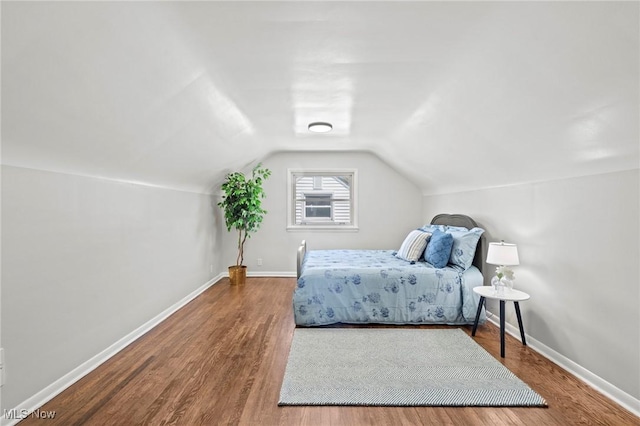 bedroom featuring baseboards, wood finished floors, and vaulted ceiling