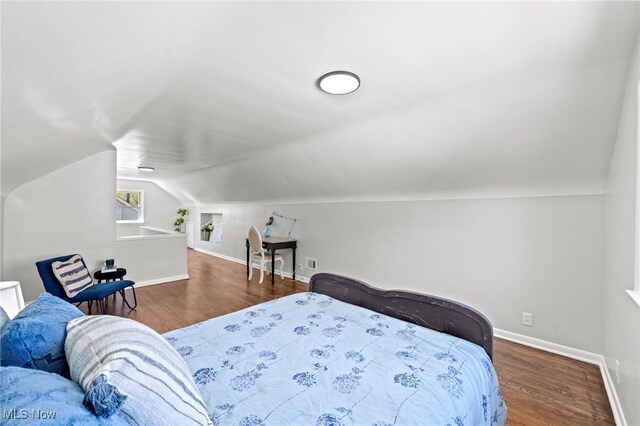 bedroom with baseboards, vaulted ceiling, wood finished floors, and visible vents