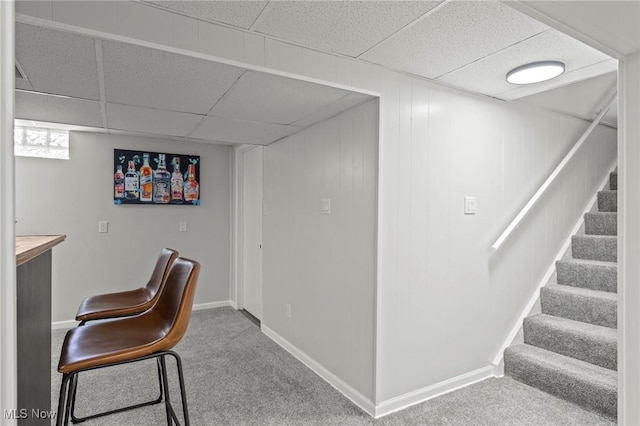 interior space with baseboards, a drop ceiling, stairs, and carpet flooring