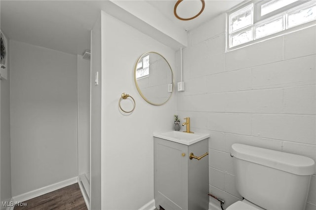 bathroom with a healthy amount of sunlight, vanity, toilet, and wood finished floors