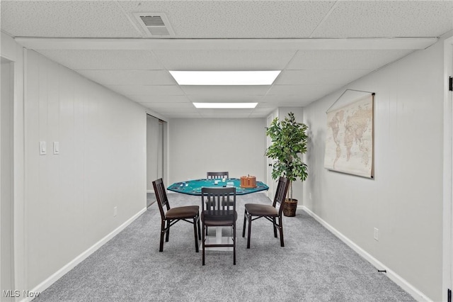 carpeted dining space with visible vents, a paneled ceiling, and baseboards