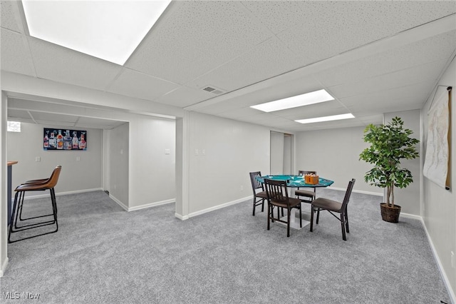 carpeted dining room with baseboards, a drop ceiling, and visible vents