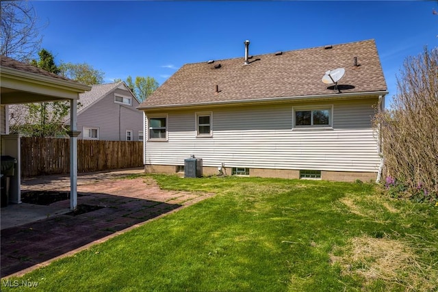 rear view of house featuring fence, central AC unit, a yard, and a patio area