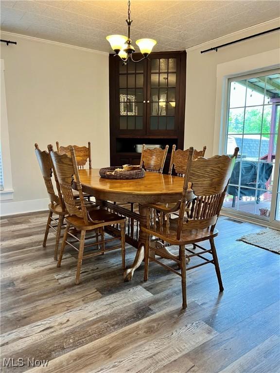 dining room with crown molding, baseboards, an inviting chandelier, and wood finished floors