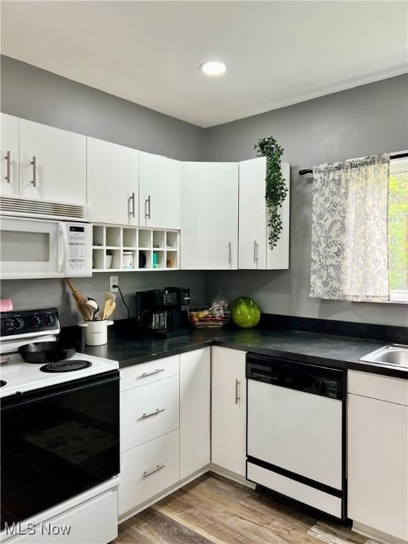 kitchen featuring white cabinets, open shelves, dark countertops, white appliances, and wood finished floors