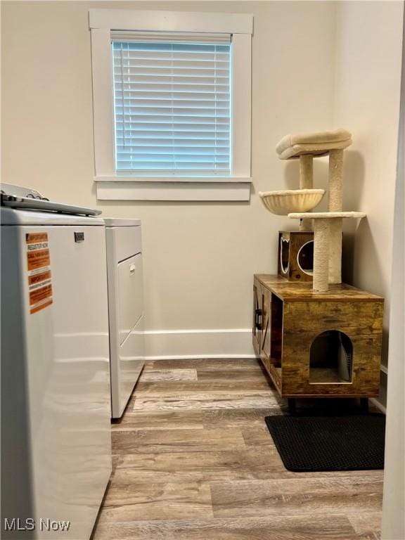 interior space featuring separate washer and dryer, baseboards, and wood finished floors
