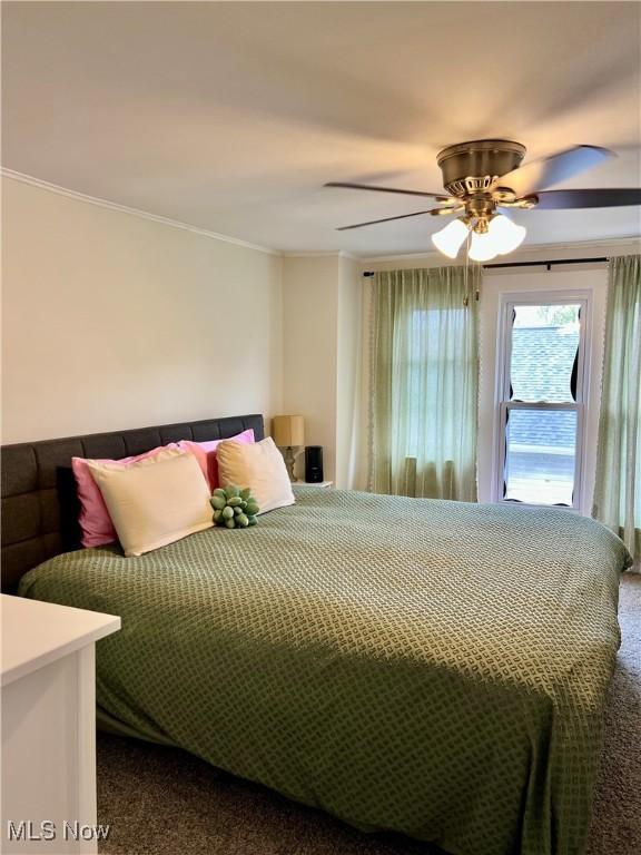 bedroom featuring ornamental molding, a ceiling fan, and dark colored carpet
