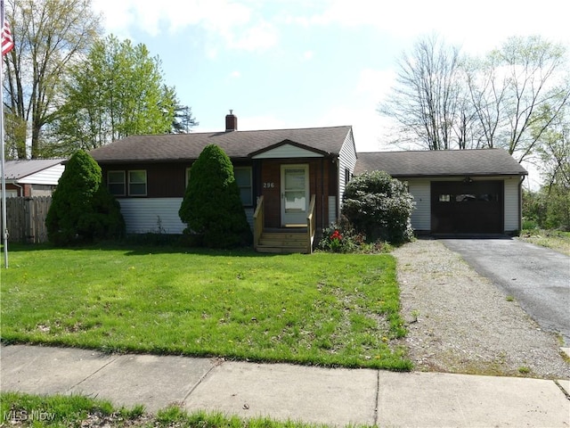 view of front of home featuring fence, an attached garage, aphalt driveway, a front yard, and a chimney