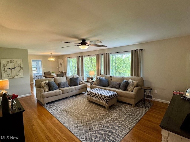 living room featuring baseboards, ceiling fan with notable chandelier, and wood finished floors