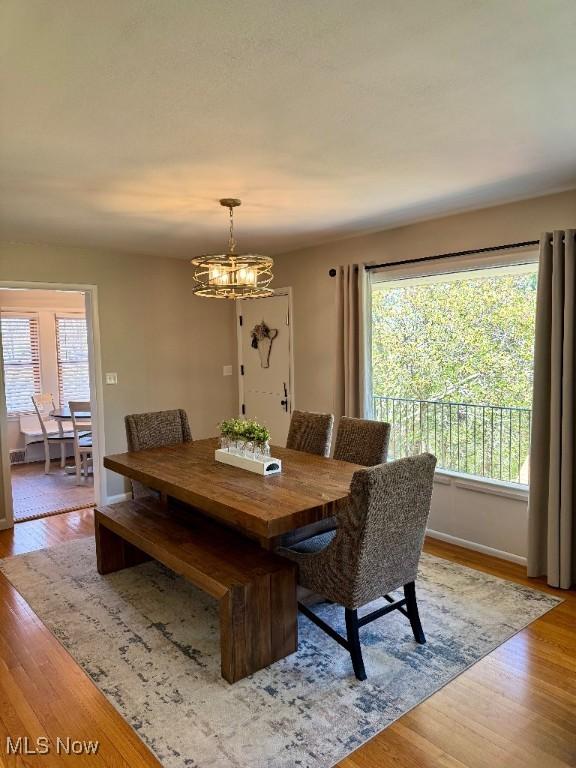 dining area with baseboards, light wood-style flooring, and a notable chandelier