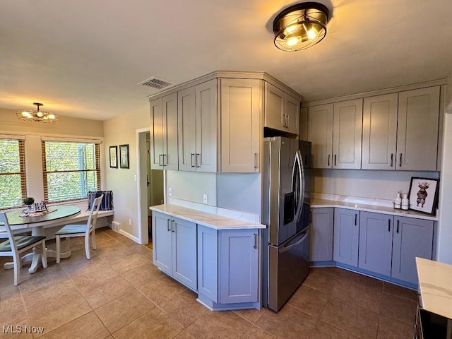 kitchen with visible vents, stainless steel refrigerator with ice dispenser, gray cabinets, tile patterned floors, and a notable chandelier