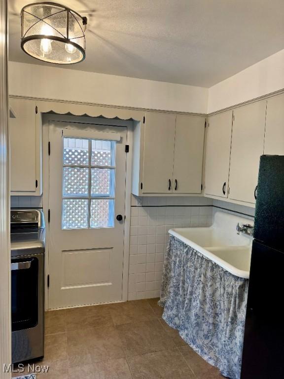 kitchen with washer / clothes dryer, tile walls, tile patterned flooring, a sink, and freestanding refrigerator