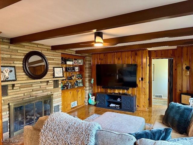 living area with visible vents, wood walls, a brick fireplace, and a ceiling fan