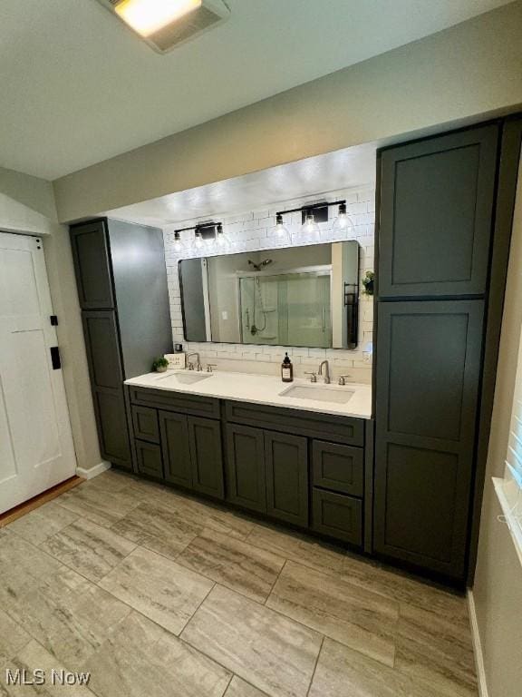 full bathroom featuring double vanity, a sink, backsplash, and a shower stall