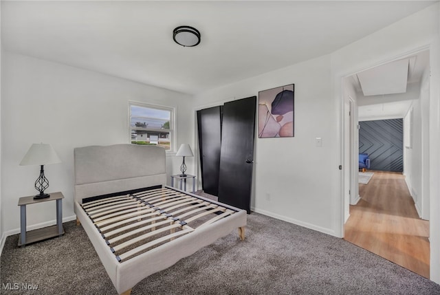 bedroom featuring a closet, baseboards, attic access, and carpet flooring