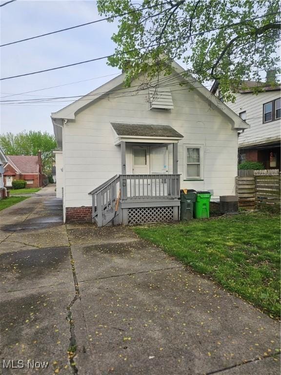back of property with fence, covered porch, and driveway