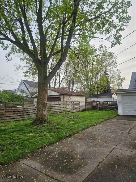 view of yard featuring fence, driveway, and a garage