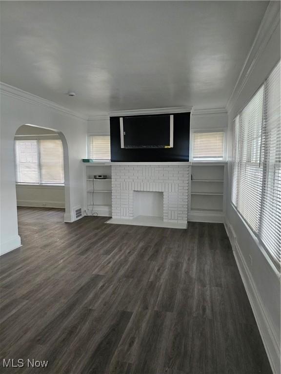 unfurnished living room featuring baseboards, visible vents, ornamental molding, and a healthy amount of sunlight