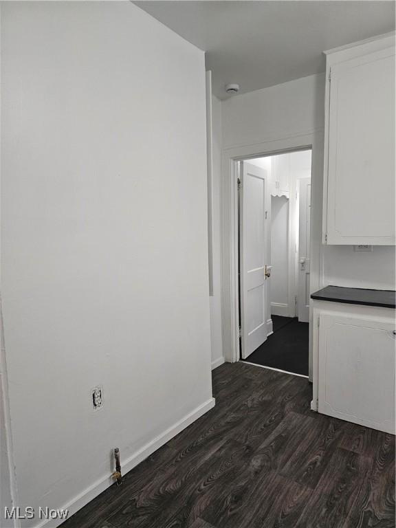 hall featuring baseboards and dark wood finished floors